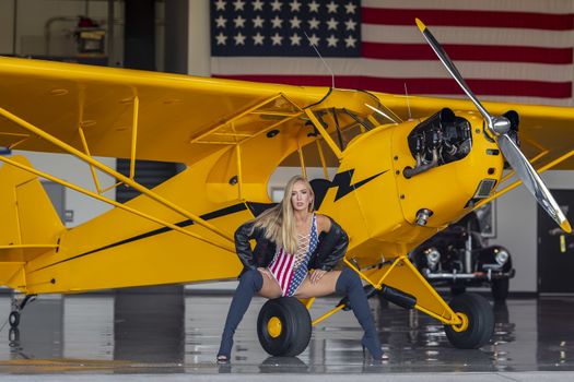 A beautiful blonde model poses with a vintage WWII aircraft