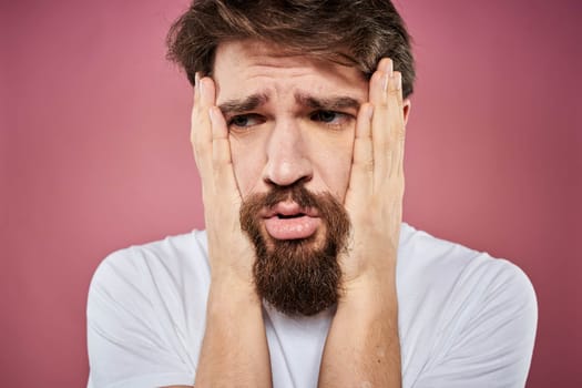 bearded man in white t-shirt emotions displeased facial expression studio pink background. High quality photo