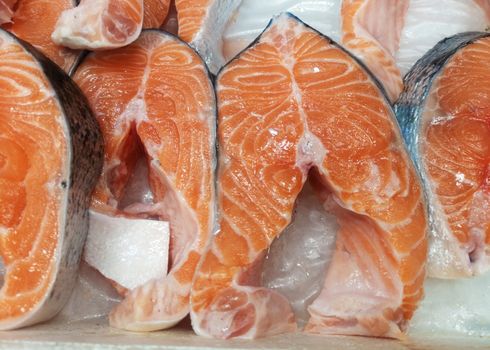 Steaks of fresh salmon red fish on the store counter in ice.