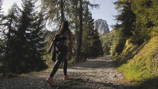 Tourist hiking in a sunny summer day with blue skies at Muttereralm, one of the mountains of the Austrian alps.