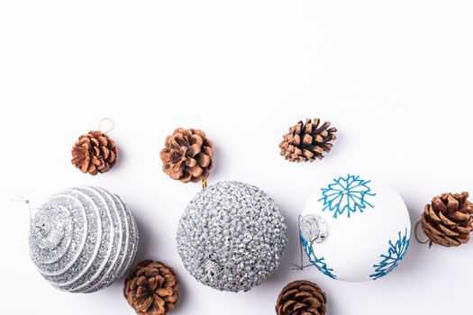 Christmas New Year composition. Gifts, fir tree cones, silver ball decorations on white background. Winter holidays concept. Top view copy space