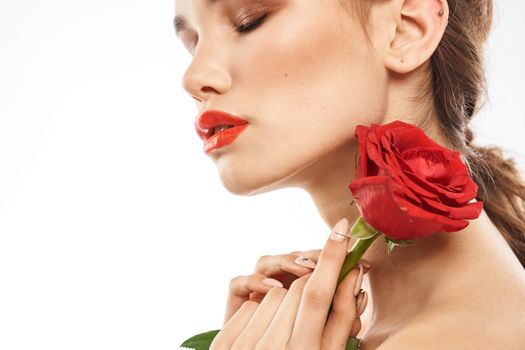 Beautiful woman with red rose near face makeup naked shoulders portrait. High quality photo