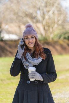 A gorgeous blonde model enjoys a winters day outdoors while drinking her favorite drink and talking on her cellphone