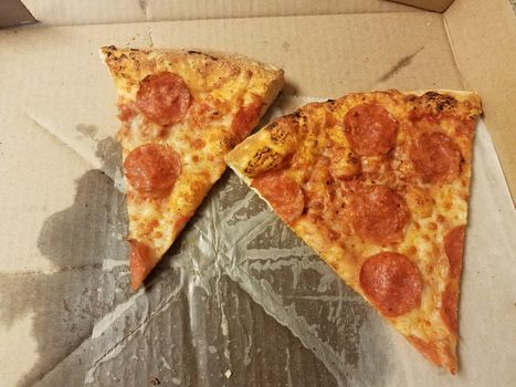 slices of pepperoni pizza with grease in cardboard box