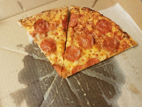 slices of pepperoni pizza with grease in cardboard box