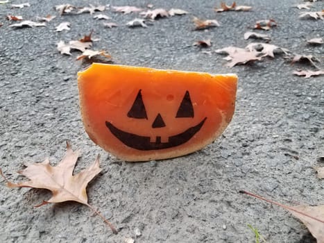orange cheese with Halloween pumpkin face and asphalt and leaves