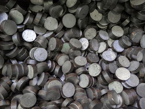 A pile of sawed cylindrical steel workpieces. Full frame close-up abstract industrial background.