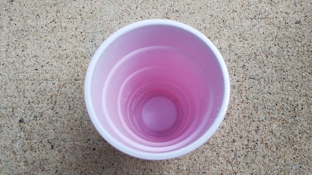 inside white and red plastic drinking cup on grey cement