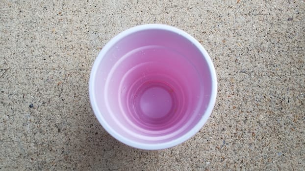 inside white and red plastic drinking cup on grey cement