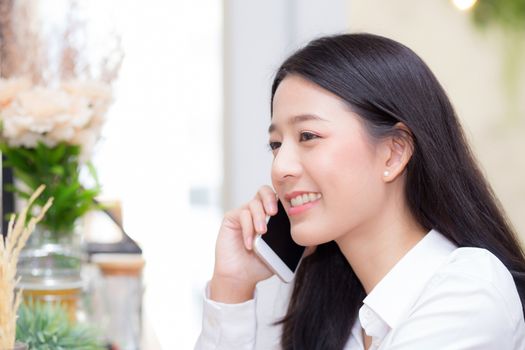 Beautiful young asian woman talking phone and smile in the coffee shop, businesswoman sitting in cafe free time, freelancer female calling telephone, communication concept.