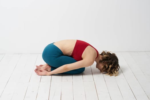 the girl is engaged in yoga on a light background Red T-shirt gesticulating with his hands. High quality photo