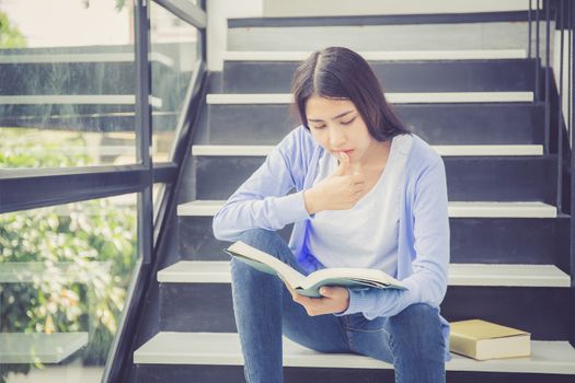 Beautiful of portrait asian young woman holding book, girl tired and bored reading book studying for exams, education and lifestyle concept.