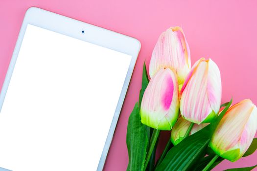 Beautiful of yellow tulip flower and tablet, with flat lay on the pink background, top view, copy space, mother day and holiday concept.