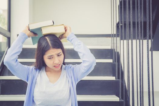 Beautiful of portrait asian young woman holding book, girl tired and bored reading book studying for exams, education and lifestyle concept.