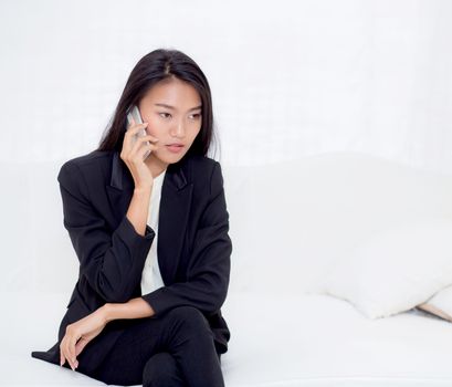 Beautiful young asian woman talking phone and smile in the living room, businesswoman sitting on sofa,businesswoman calling telephone, communication concept.