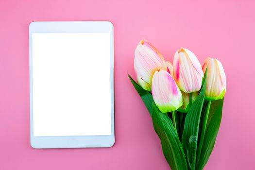 Beautiful of yellow tulip flower and tablet, with flat lay on the pink background, top view, copy space, mother day and holiday concept.