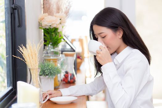 Beautiful  young asian woman drinking coffee and smile in the morning at cafe, girl sitting in coffee shop for breakfast and leisure during free time.