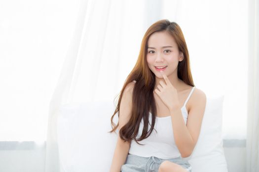 Portrait beautiful young asian woman sitting and smile the window at bedroom while wake up with sunrise at morning, lifestyle and relax concept.