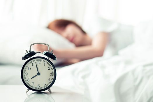Beautiful asian young woman turn off alarm clock in good morning, wake up for sleep with closeup foreground alarm clock, relax and lifestyle concept.