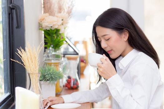 Beautiful  young asian woman drinking coffee and smile in the morning at cafe, girl sitting in coffee shop for breakfast and leisure during free time.