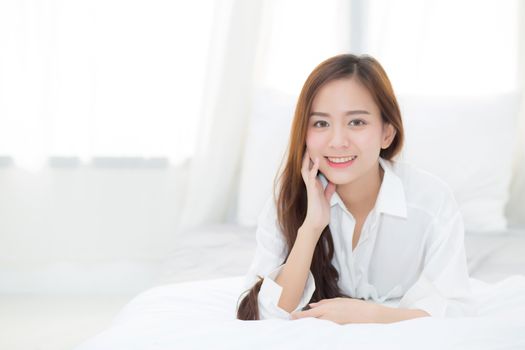 Beautiful portrait young asian woman lying and smile while wake up with sunrise at morning, lifestyle and relax concept.