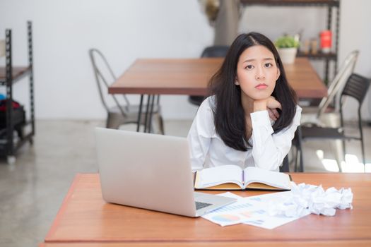 Beautiful of portrait asian young woman working online on laptop sitting and crumpled paper on table at coffee shop, professional female freelance using notebook computer, communication concept.