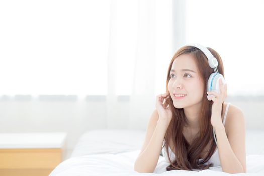 Beautiful asian young woman enjoy listen music with headphone while lying in bedroom, relax girl with earphone internet online, leisure and technology concept.