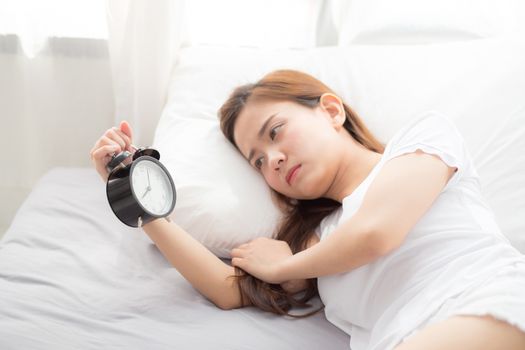 Beautiful asian young woman turn off alarm clock in good morning, wake up for sleep, girl holding alarm clock, time and lifestyle concept.