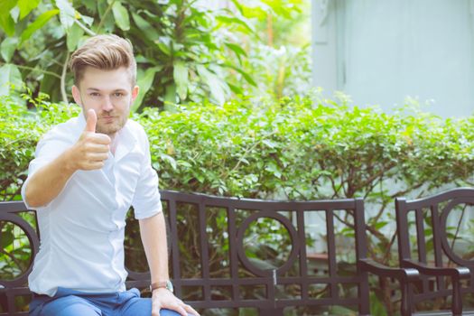 Portrait of handsome man smile with happy and gesture thumbs up at the park, business success concept.