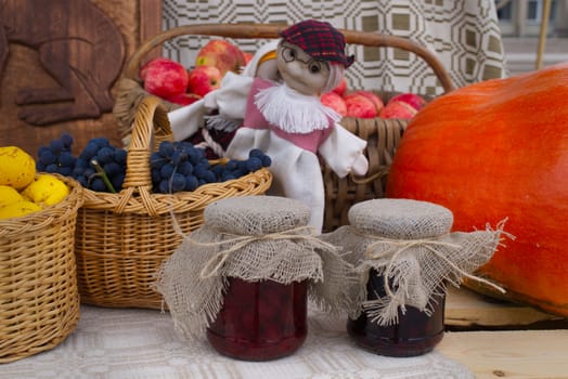 Autumn still life with fresh seasonal produce including apples, pumpkin and berries, home made preserves and handicraft arranged on a rustic table