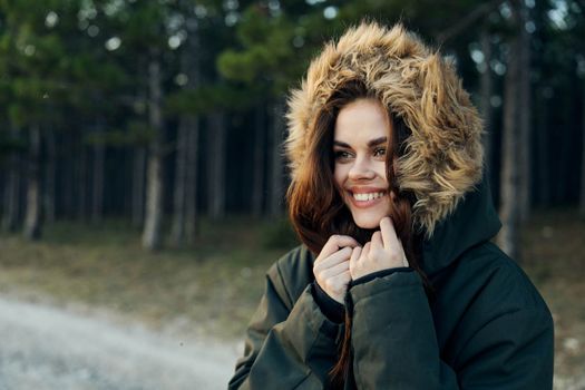 Woman jacket with a hood smile look aside the fresh air on the background of the forest. High quality photo