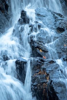 Power and explosive energy in this long exposure abstract, colorful autumn leaves dot the black rocks.