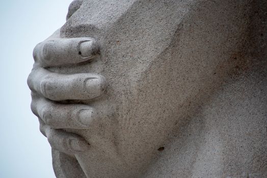 Beautiful fingers and hand on crossed arms of Dr. King. Beautiful pink granite and pale blue sky, Washington, DC.