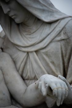 Beautiful stone pieta in a Victorian cemetery. Full frame image in natural light. Selective focus on joined hands.