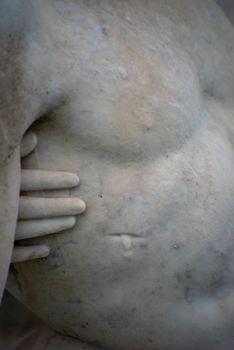 Close up of cemetery statue Jesus's wounded side and Mary's hand. Beautiful stone pieta statue in Victorian cemetery.