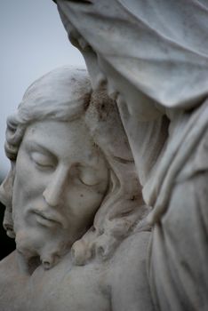 Beautiful stone pieta in a Victorian cemetery. Full frame image in natural light. Selective focus on face of Jesus.