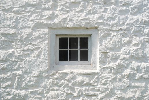 Ancient construction style using wooden dowels and six-pane glass. Fresh whitewash on stone facade.