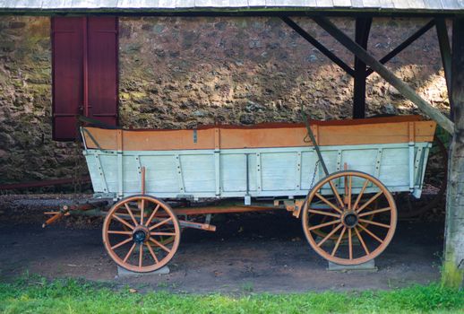 Wagon sits by a beautiful stone wall with red window shutters. Beautiful restored construction and color at Hopewell Furnace National Historic Site in Pennsylvania.