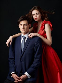 Pin-up couple portrait woman in red dress man in suit on dark background romance