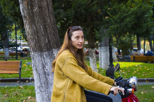 Woman on the scooter in the park, beautiful and casual