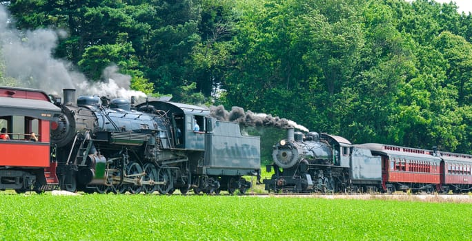 2 Antique Steam Passenger Train Puffing Lots of Black Smoke along Amish Countryside with Green Fields