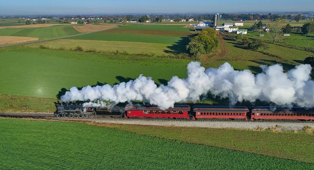 Aerial View of Steam Passenger Train Puffing Smoke Traveling in Amish Countryside in an Early Morning