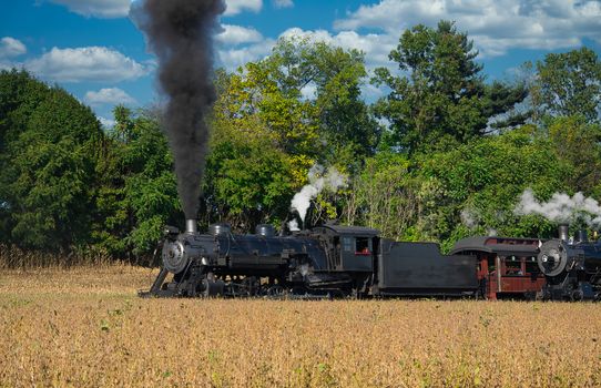 Close up of an Antique Steam Freight Train Puffing Smoke and Steam While going Thru Amish Countryside