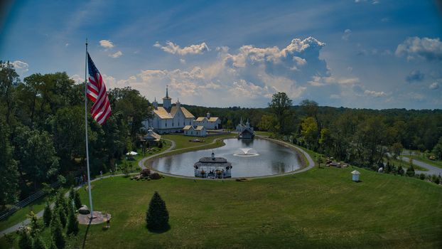 Aerial View of Old Restored White Barns with Cupolas and 5 Pointed Stars by a Pond with a Fountain