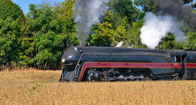 Close up of an Antique Steam Freight Train Puffing Smoke and Steam While going Thru Amish Countryside