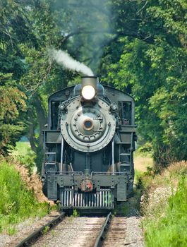Close Up of an Antique Steam Passenger Train Puffing along Amish Countryside with Green Fields