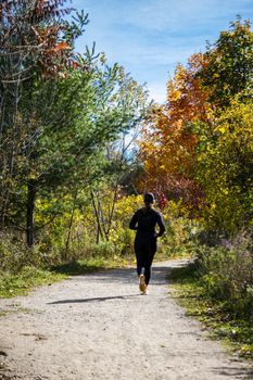 The girl hurries home along the path in the forest and does not notice the beauty of the autumn forest