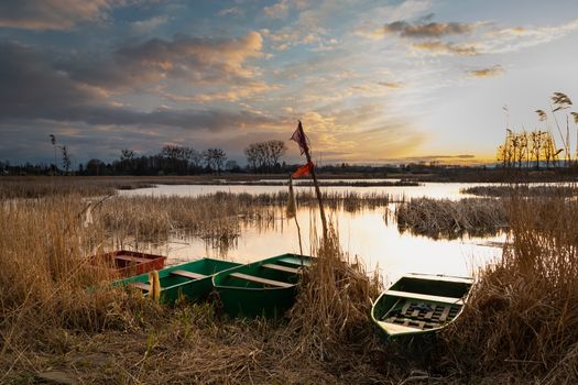 Fishing boats on the lake shore and cloudy evening sky