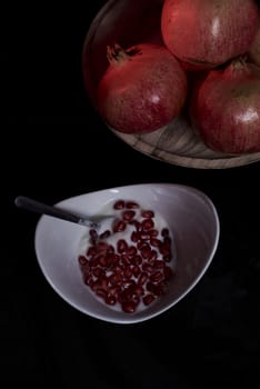 Pomegranates in wooden plate and seeds in bowl with yogurt, Pomegranates in wooden plate and seeds in bowl with yogurt,
