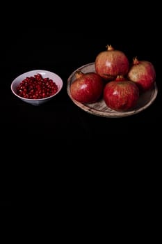 Pomegranate close-up with seeds in bowl close-up, Black background, macro photography